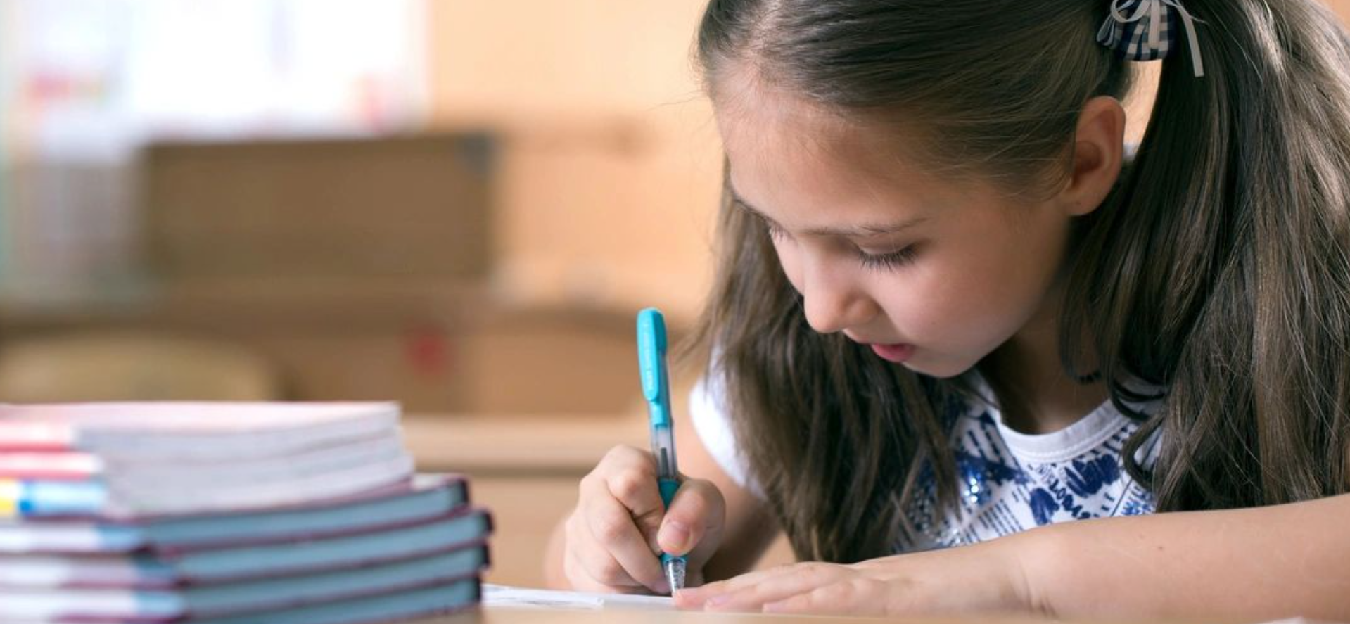 Girl writing in classroom, focused.